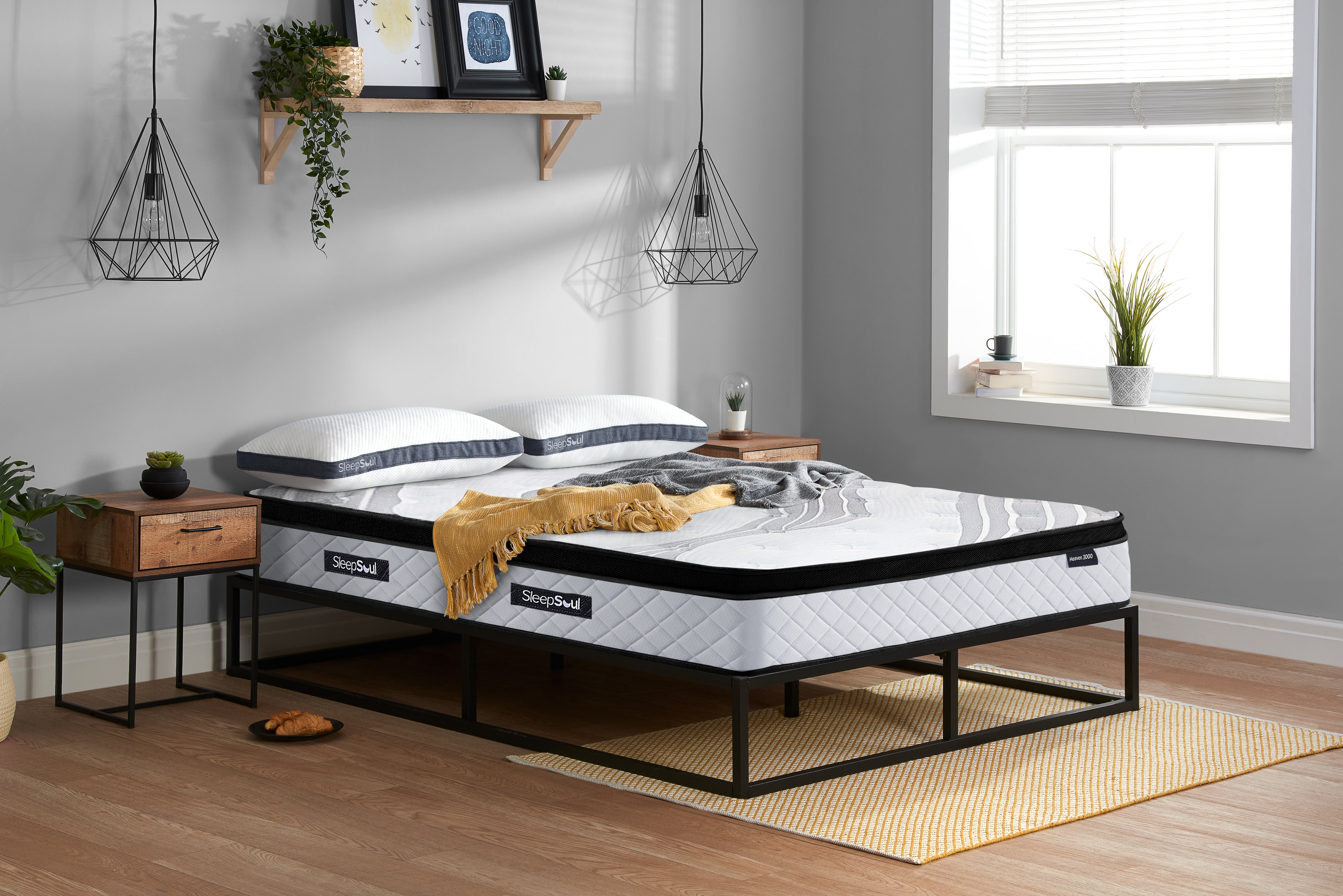 SleepSoul Heaven 3000 pocket spring mattress on a metal bed frame in minimalist bedroom with side tables, black metal hanging lights and window light