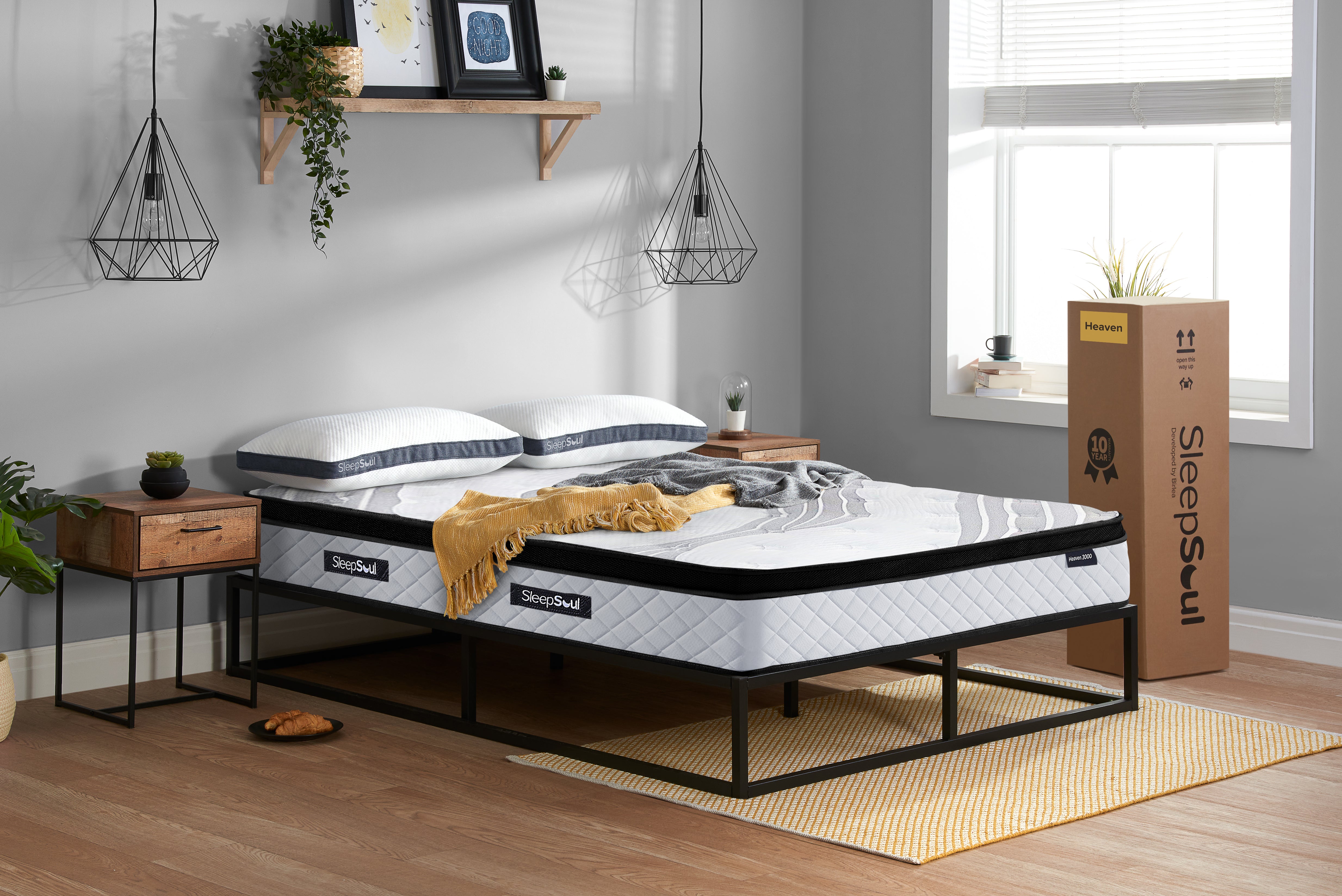 SleepSoul Heaven 3000 pocket spring mattress on a metal bed frame in minimalist bedroom, with mattress box alongside, shelf with frames and plants
